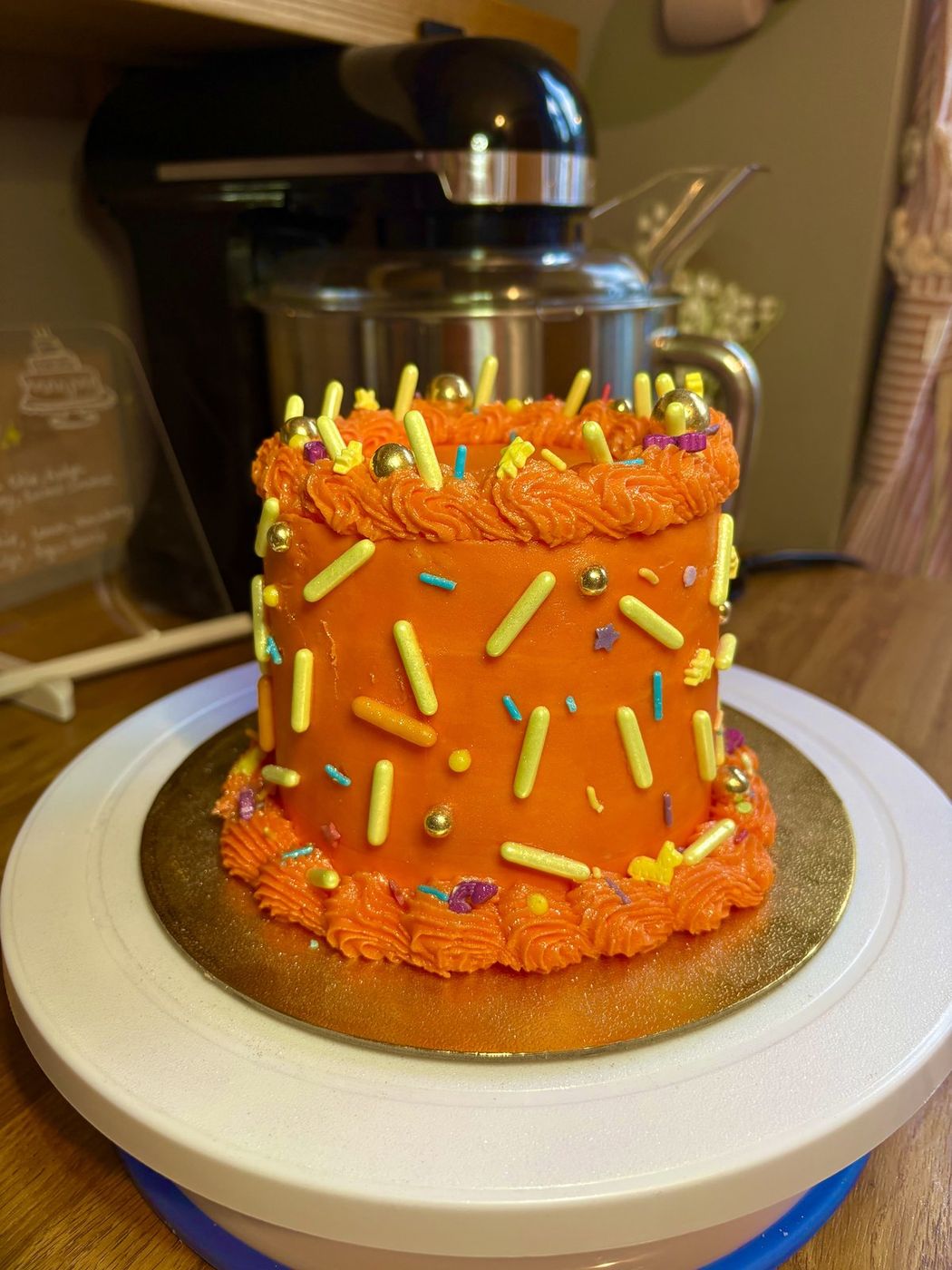 Orange buttercream celebration cake with rainbow sprinkles and gold pearls
