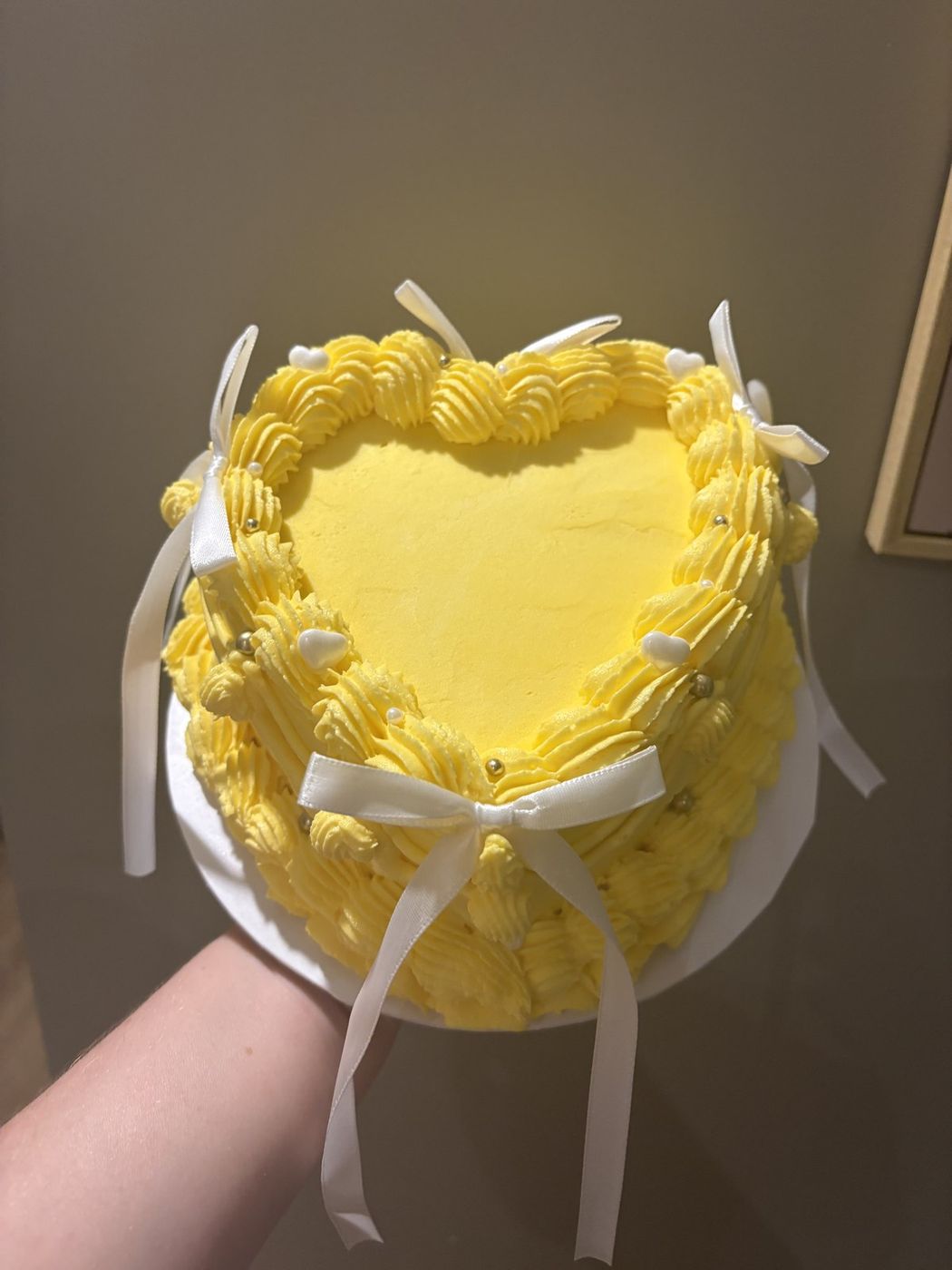 Yellow buttercream heart-shaped cake with an ivory satin bow