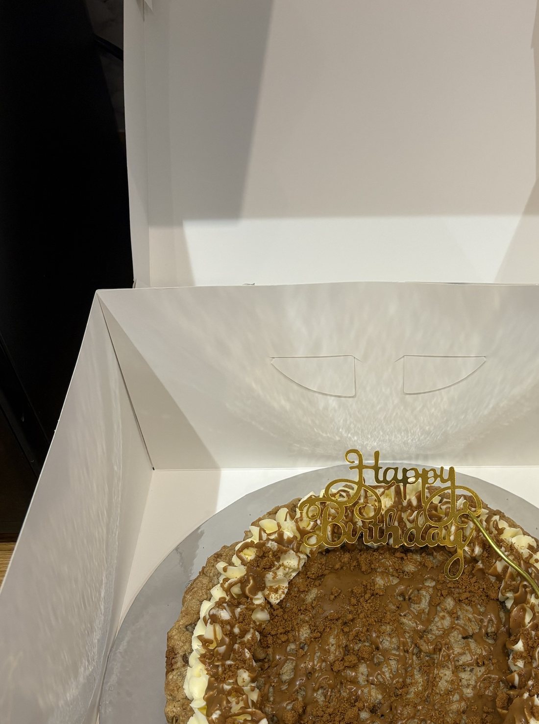 Boxed giant Biscoff cookie cake with a piped buttercream border, Biscoff drizzle and crumb and a gold Happy Birthday topper