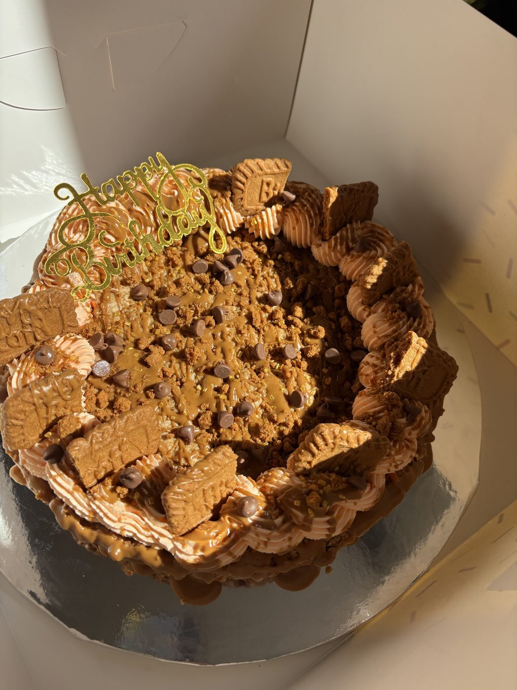 Giant Biscoff birthday cookie cake with piped buttercream, Biscoff biscuits, chocolate chips and a gold Happy Birthday topper