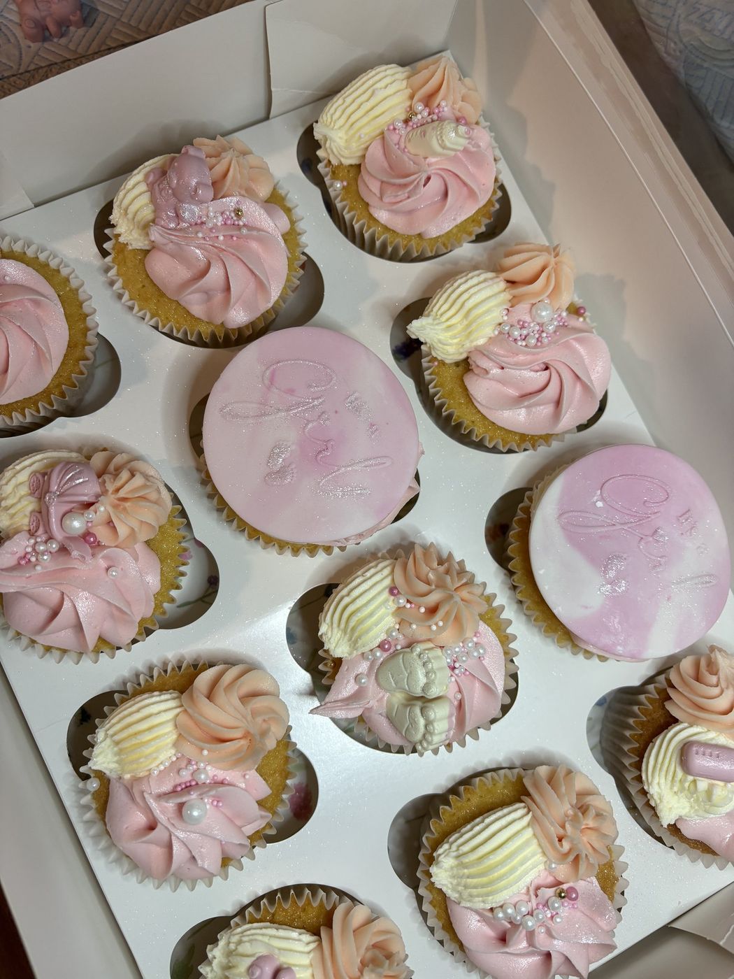 Pink and peach baby shower cupcakes with baby feet and pram decorations