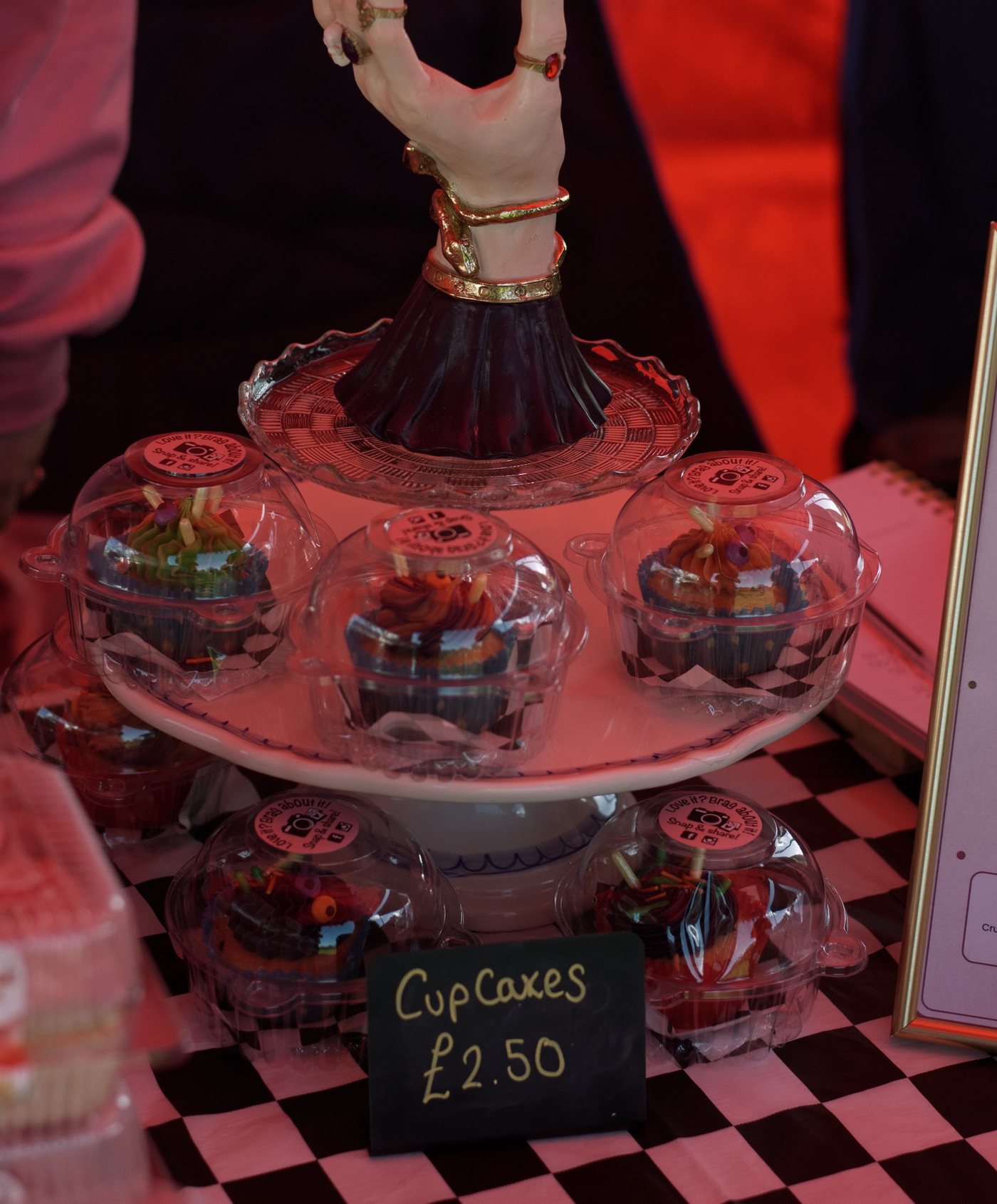 Halloween cupcakes in individual domes on a cake stand at the Crumb & Chaos Cakes market stall