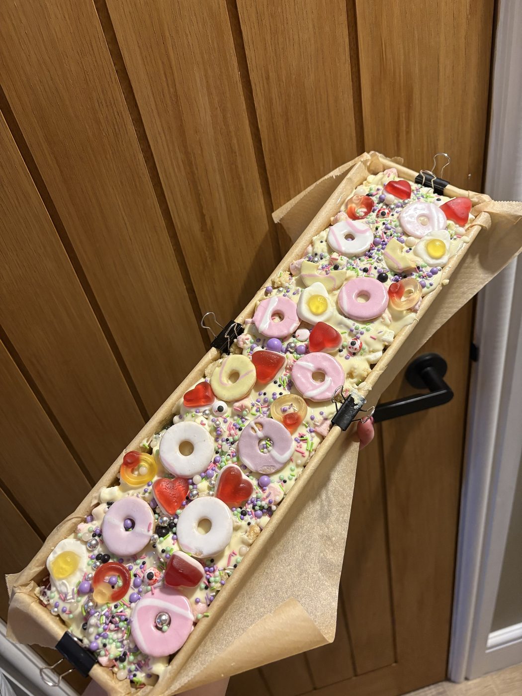 White chocolate rocky road tray bake topped with party ring biscuits, jelly sweets and pastel sprinkles